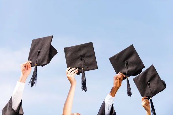 Four hands holding mortar boards — Stock Photo, Image