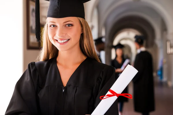 Woman in graduation gown holding diploma — Stock Photo, Image