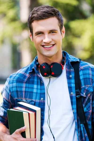 Joven sosteniendo libros y sonriendo — Foto de Stock