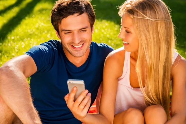 Pareja mirando el teléfono móvil en el parque — Foto de Stock