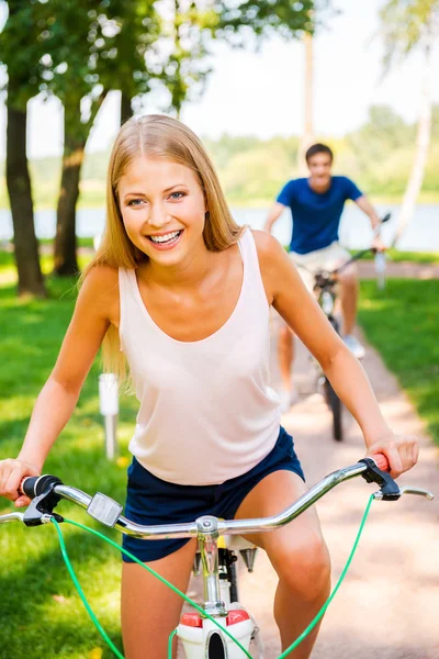 Mujer montar en bicicleta mientras su novio montar en bicicleta en el fondo —  Fotos de Stock