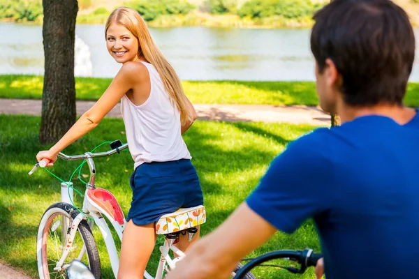 Mujer montando bicicleta y mirando a su novio montando detrás —  Fotos de Stock