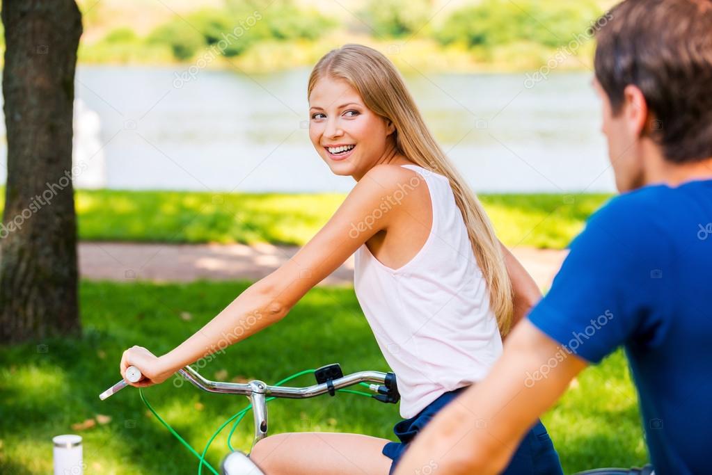 Woman riding her bicycle while boyfriend riding behind her
