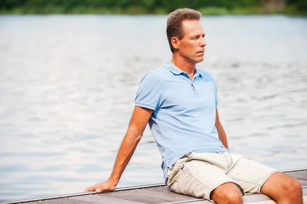 Miło dojrzały mężczyzna siedzący przy nabrzeżu — Zdjęcie stockowe