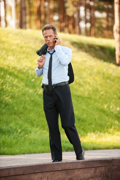 Бизнесмен разговаривает по мобильному телефону в парке — стоковое фото