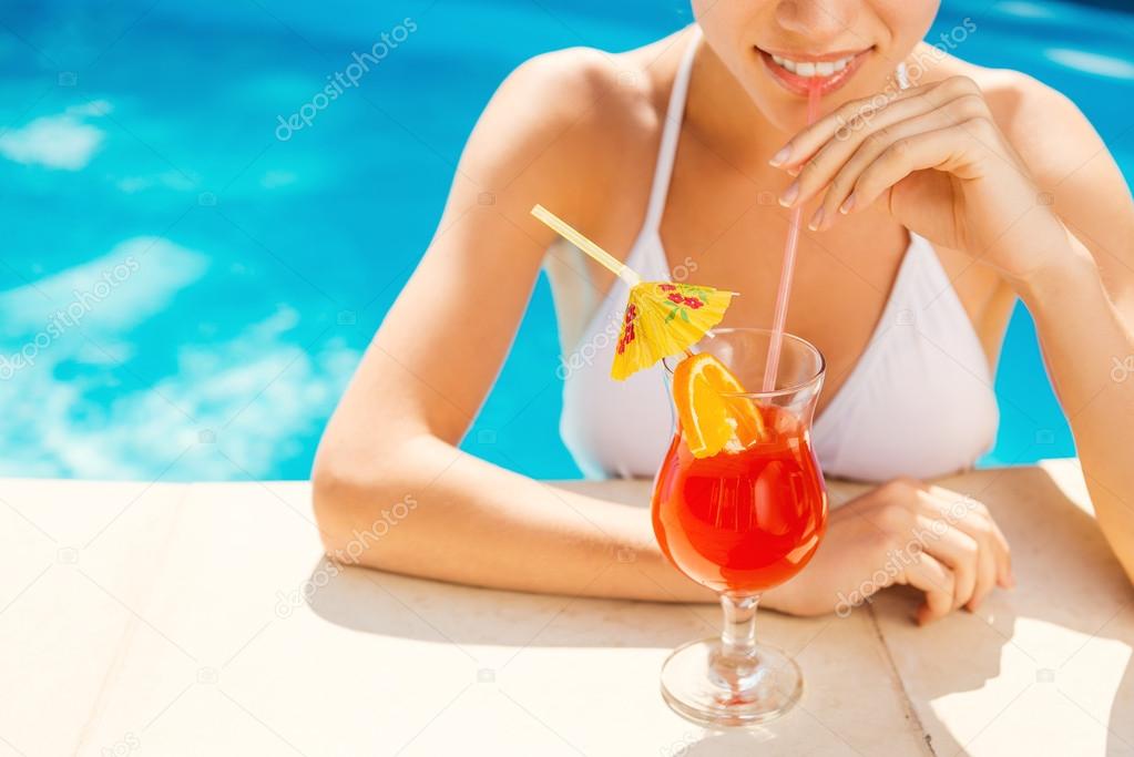 Woman in white bikini drinking cocktail