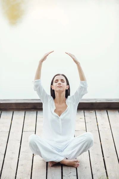 Woman in white clothing sitting in lotus position — Stock Photo, Image