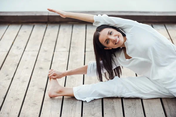 Woman in white clothing performing yoga — Stock Photo, Image