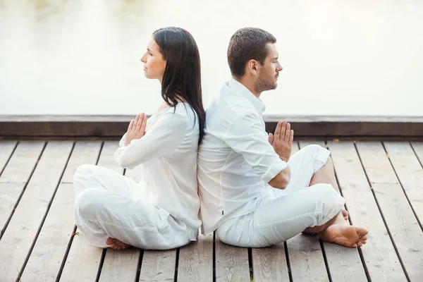 Casal em roupas brancas meditando ao ar livre — Fotografia de Stock