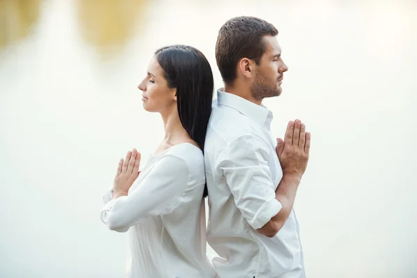 Couple in white clothing meditating outdoors