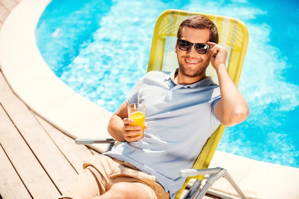 Mann sitzt mit Glas Saft im Liegestuhl — Stockfoto