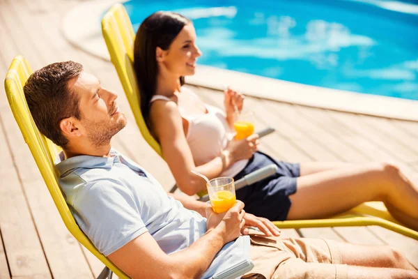 Pareja sosteniendo cócteles junto a la piscina — Foto de Stock