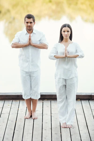 Casal em roupas brancas meditando — Fotografia de Stock