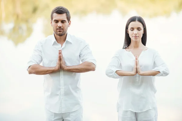 Пара в білому одязі медитує — стокове фото