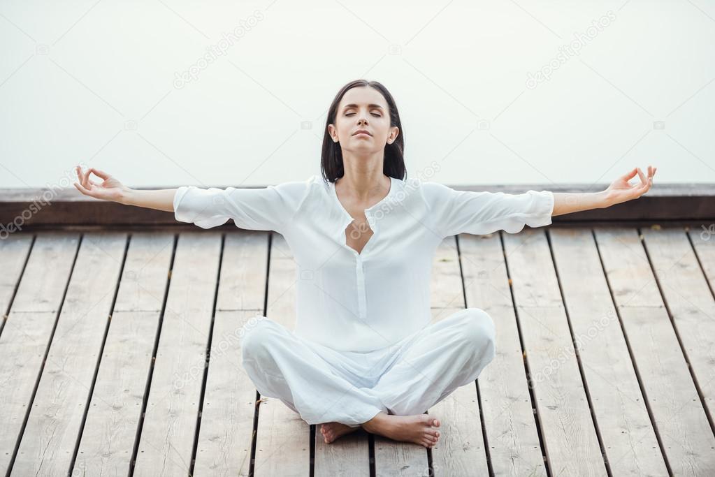 Woman in white clothing sitting in lotus position