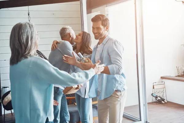 Smiling senior parents meeting young couple inside the house — Stock Photo, Image