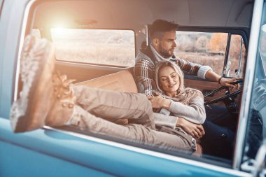 Genç ve güzel bir çift, eski mini minibüsün ön koltuklarında otururken birlikte araba yolculuğunun tadını çıkarıyorlar.