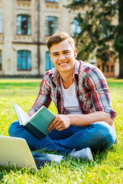 Öğrenci çimlere oturup kitap okuma