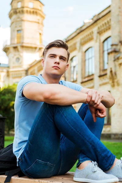Student sitting on the bench and looking away — Stock Photo, Image
