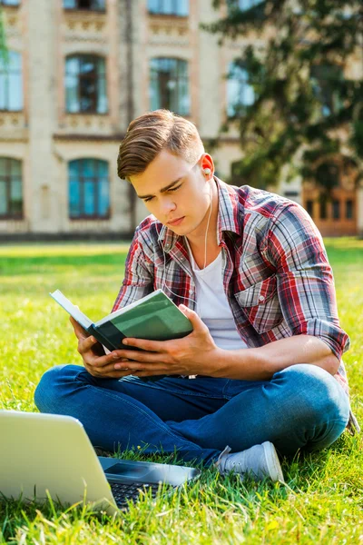 Student lezen boek op het gras — Stockfoto