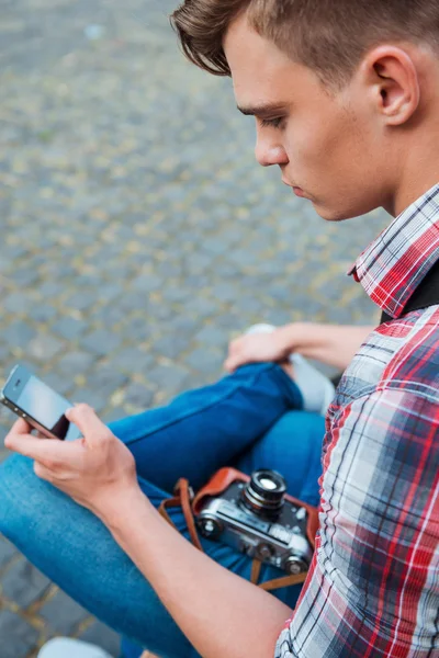 Photographer with camera typing on mobile phone — Stock Photo, Image