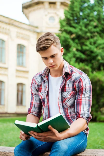 Student reading book while sitting on the bench — Stock Photo, Image