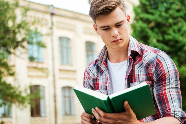 Student reading book against the university building — Stock Photo, Image