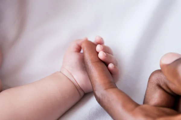 Pequeno bebê segurando pais dedo — Fotografia de Stock