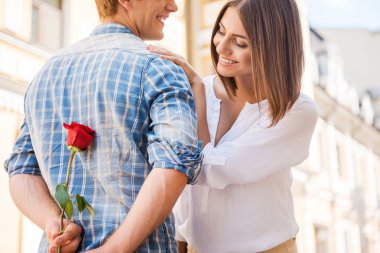 Benim için mi? Dikiz kırmızı gül ise arka planda yürüyen kadın arkadan tutan genç adam