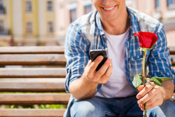 Uomo in possesso di rosa e cellulare — Foto Stock