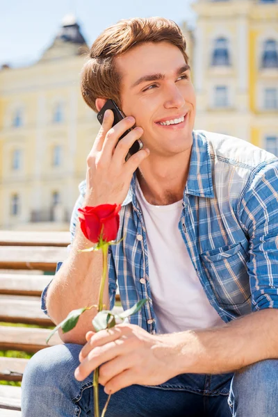 Uomo in possesso di rosa e parlando sul telefono cellulare — Foto Stock
