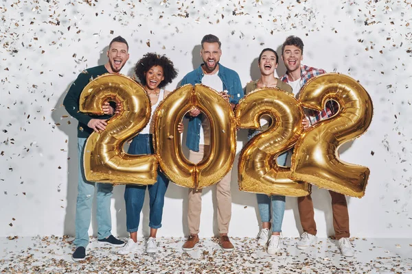 Gruppe junger schöner Menschen in lässiger Kleidung, die goldfarbene Zahlen tragen und lächeln — Stockfoto