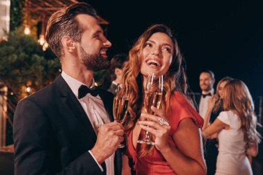 Formalite içinde genç ve güzel bir çift şampanya içerken lüks bir partide vakit geçiriyorlar.
