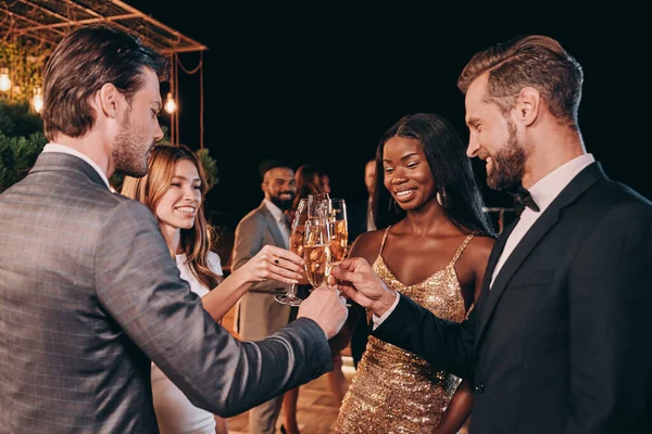 Grupo de personas en ropa formal comunicándose y sonriendo mientras pasan tiempo en una fiesta de lujo — Foto de Stock