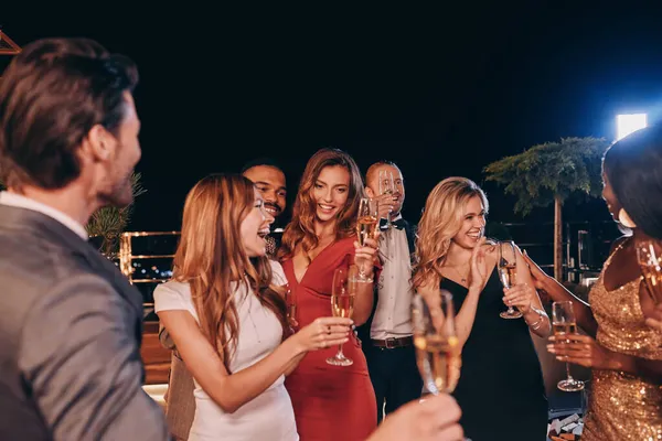 Група людей у формальному одязі спілкується і посміхається, проводячи час на розкішній вечірці — стокове фото