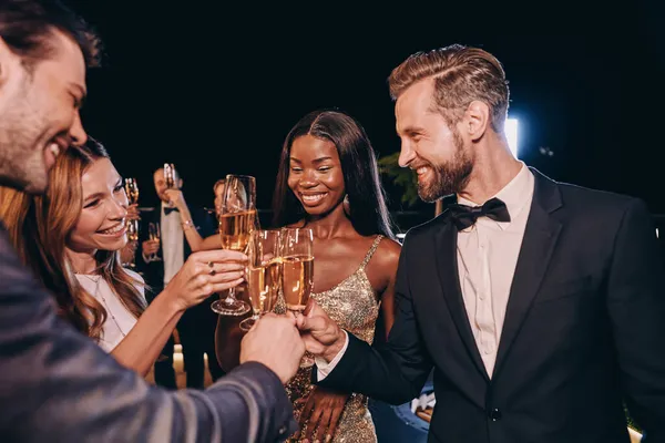 Група красивих людей у формальному одязі з тостами з шампанським і посміхаючись, проводячи час на розкішній вечірці — стокове фото