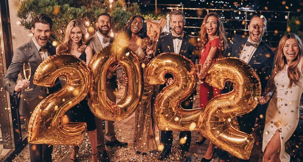 Gruppe schöner Menschen in Formalbekleidung, die goldfarbene Zahlen tragen und lächeln — Stockfoto