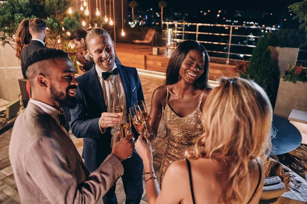 Grupo de personas en ropa formal comunicándose y sonriendo mientras pasan tiempo en una fiesta de lujo — Foto de Stock