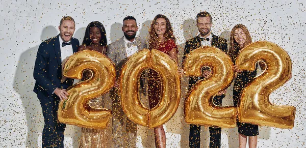 Gruppe schöner Menschen in Formalbekleidung, die goldfarbene Zahlen tragen und lächeln — Stockfoto