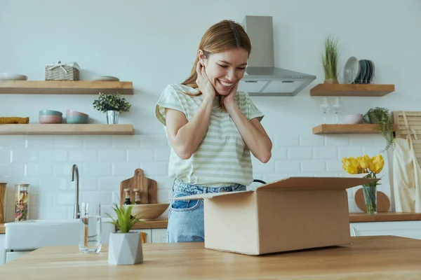 Sorpresa Giovane Donna Disimballaggio Scatola Mentre Piedi Presso Cucina Domestica — Foto Stock