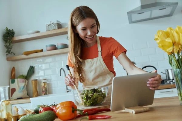 Självsäker Ung Kvinna Matlagning Och Använda Digital Tablett När Står — Stockfoto