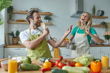 Genç ve güzel bir çift mutfakta birlikte yemek pişirirken şarkı söyleyip eğleniyorlar.