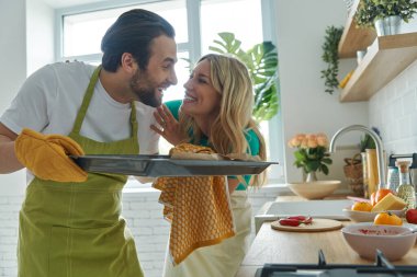 Mutlu genç çift mutfakta bir şeyler pişiriyor.