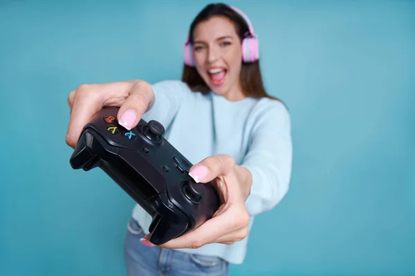 Hravá Žena Sluchátkách Drží Joystick Usmívá Zatímco Stojí Modrém Pozadí — Stock fotografie