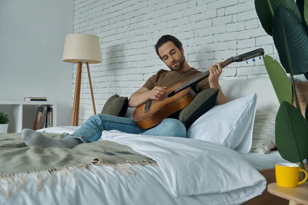 Stilig Ung Man Spelar Akustisk Gitarr Samtidigt Som Kopplar Hemma — Stockfoto