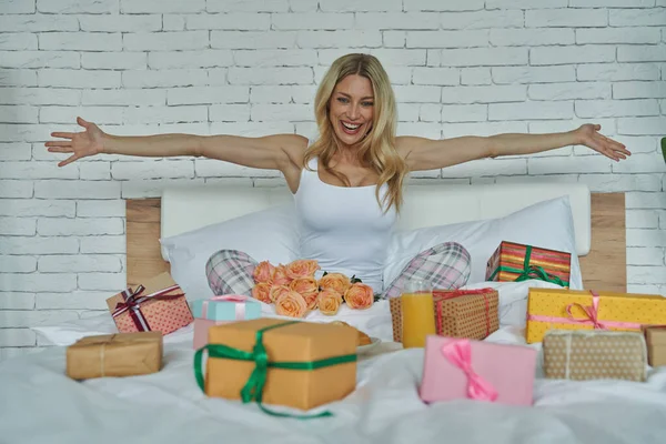 Spännande Ung Kvinna Tittar Presentförpackningar Som Ligger Runt Henne Sängen — Stockfoto