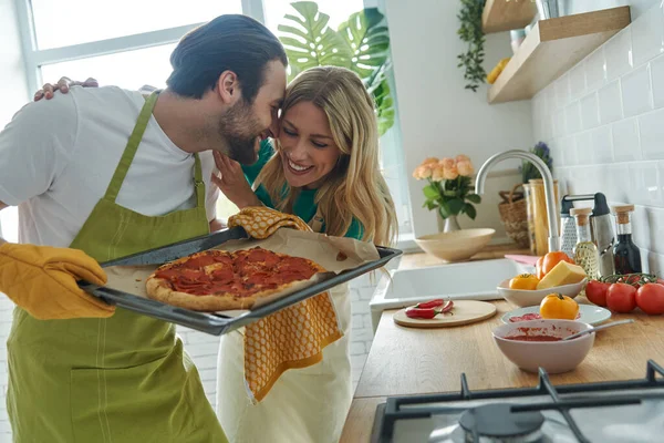 Hermosa Pareja Joven Sosteniendo Pizza Casera Sonriendo Mientras Están Pie —  Fotos de Stock