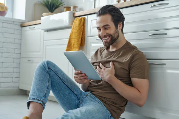 Jovem Feliz Usando Tablet Digital Enquanto Sentado Chão Perto Balcão — Fotografia de Stock