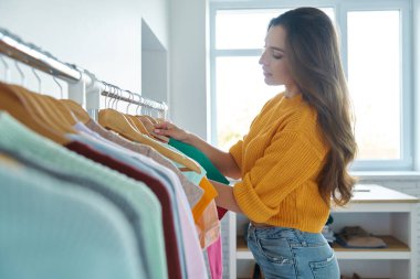 güzel genç kadın moda deposunda giysiler seçmek