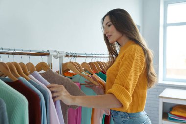 Moda mağazasında kıyafet seçen kendinden emin genç bir kadın.